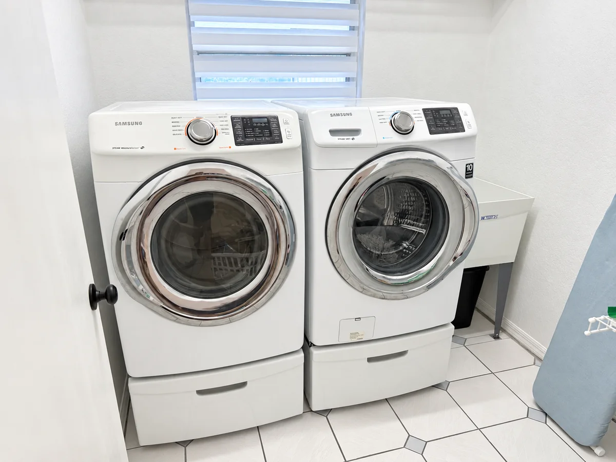 Laundry room with front-loading washer and dryer beside a utility sink
